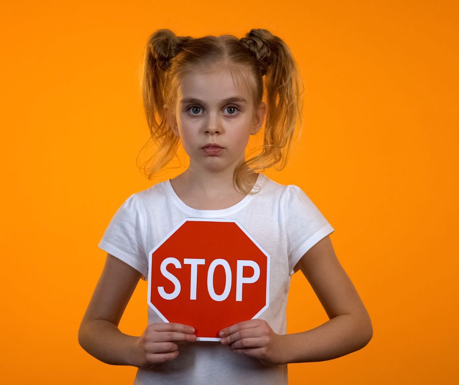 Ein Mädchen, welches ein Stopschild in seinen Händen hält.