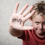Ein Junge mit erhobener Hand auf der Innenseite der Hand steht STOP.