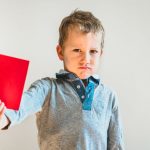 Junge, der eine rote Karte hochhält.