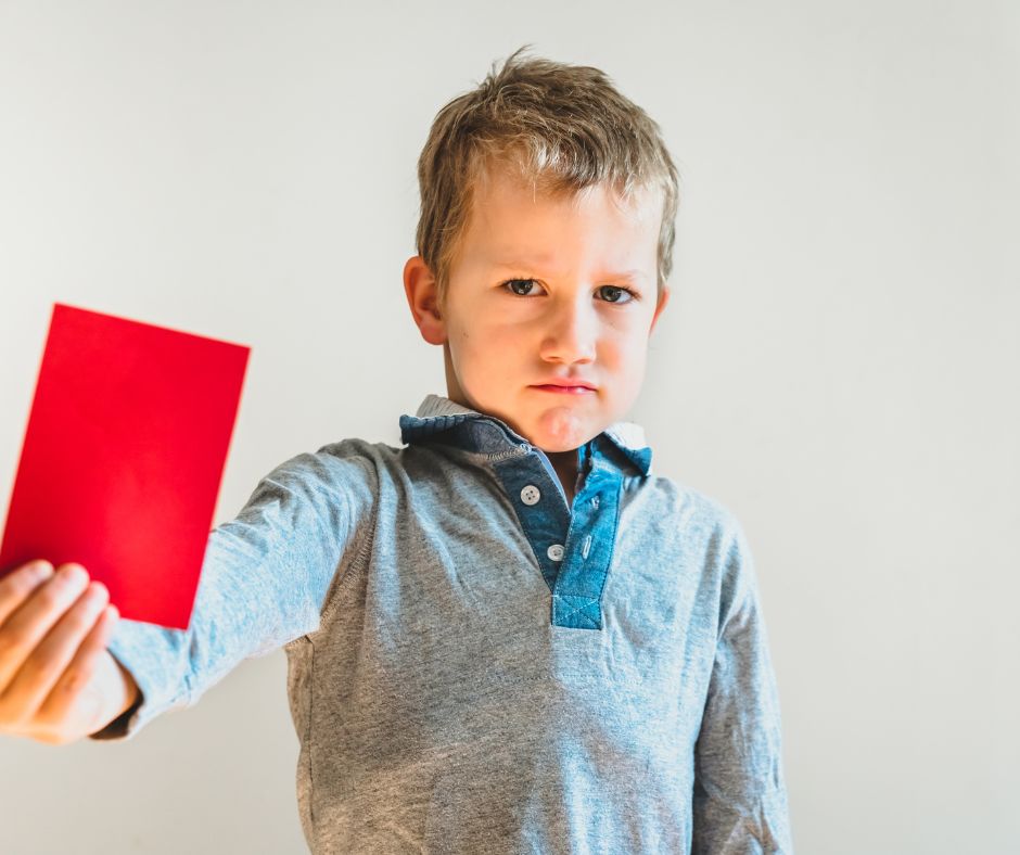 Junge, der eine rote Karte hochhält.