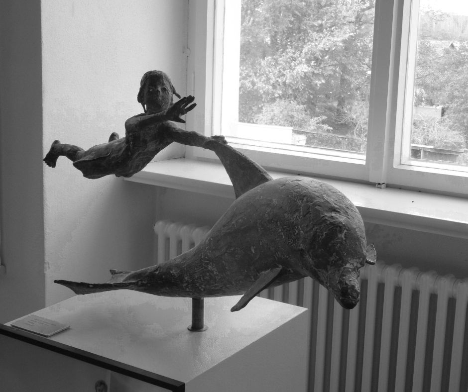 Das Bild zeigt die Skulptur des Logos der Reckahner Reflexionen: ein Kind, welches sich an der Flosse eines Delphins festhält