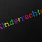 Das Wort "Kinderrechte" in bunter Kreideschrift auf schwarzem Hintergrund.