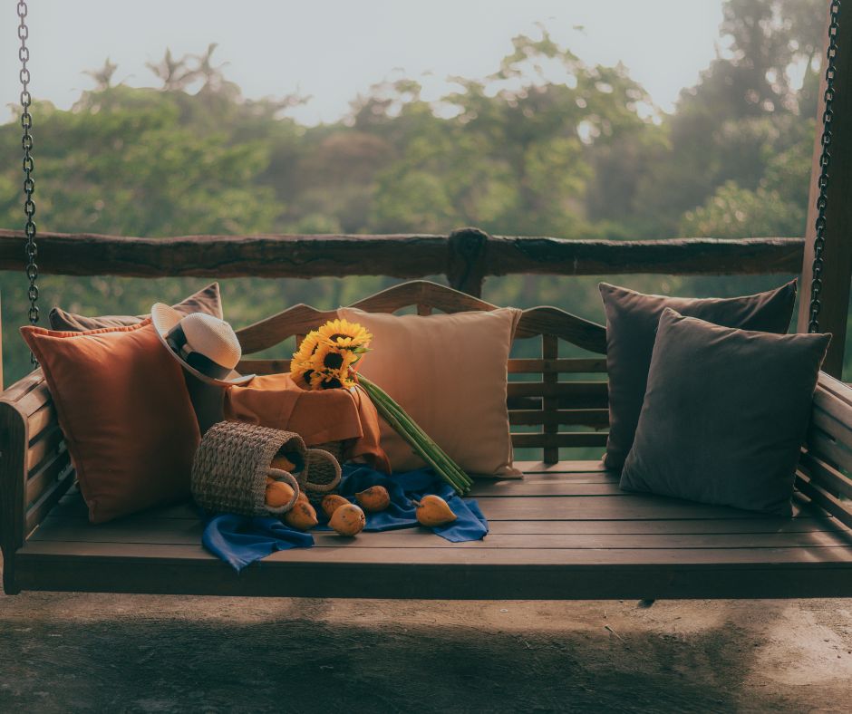 Eine Bank mit Kissen drauf. Auf einem Kissen liegt ein Hut. Vor den Kissen liegt ein Korb mit ausgeschütteten Quitten.