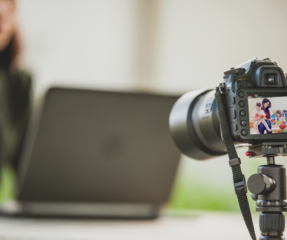 Ein aufgeklappter Laptop im Hintergrund, davor eine Kamera.